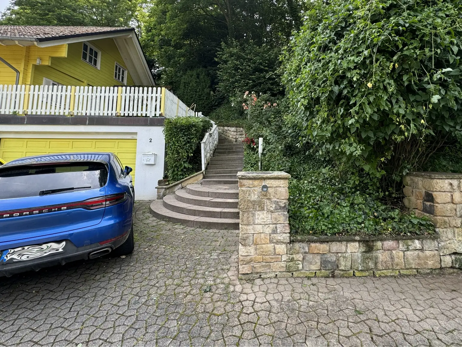 Freigeschnittene Treppenanlage und gepflegte Hecken an derselben Hofeinfahrt
