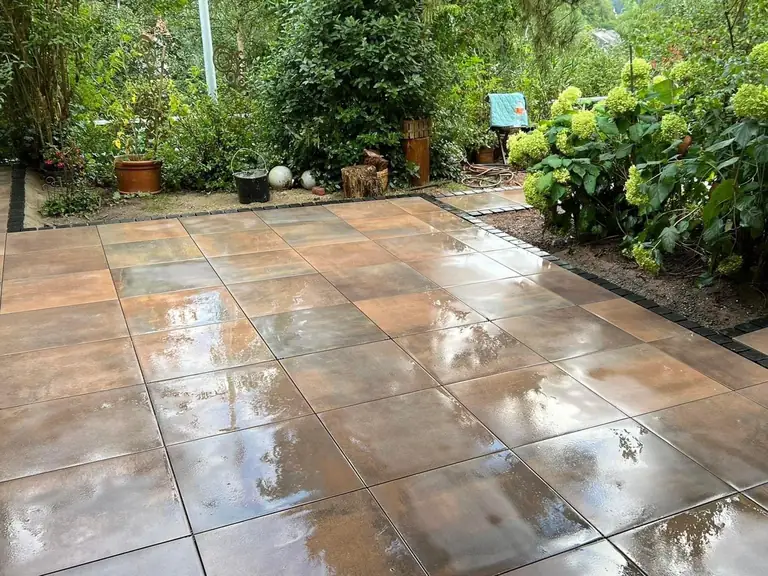 Fertige Terrasse mit großformatigen Platten, umgeben von Bepflanzung