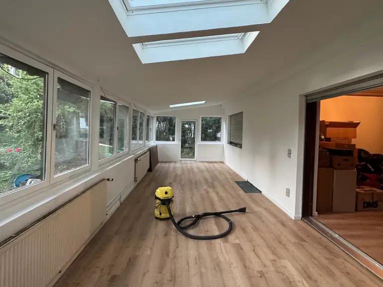 Heller Wintergarten mit Dachfenstern und neu verlegtem Boden in Holzoptik