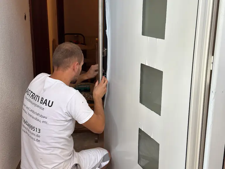 Handwerker von Kastrati bei der Montage einer Haustür